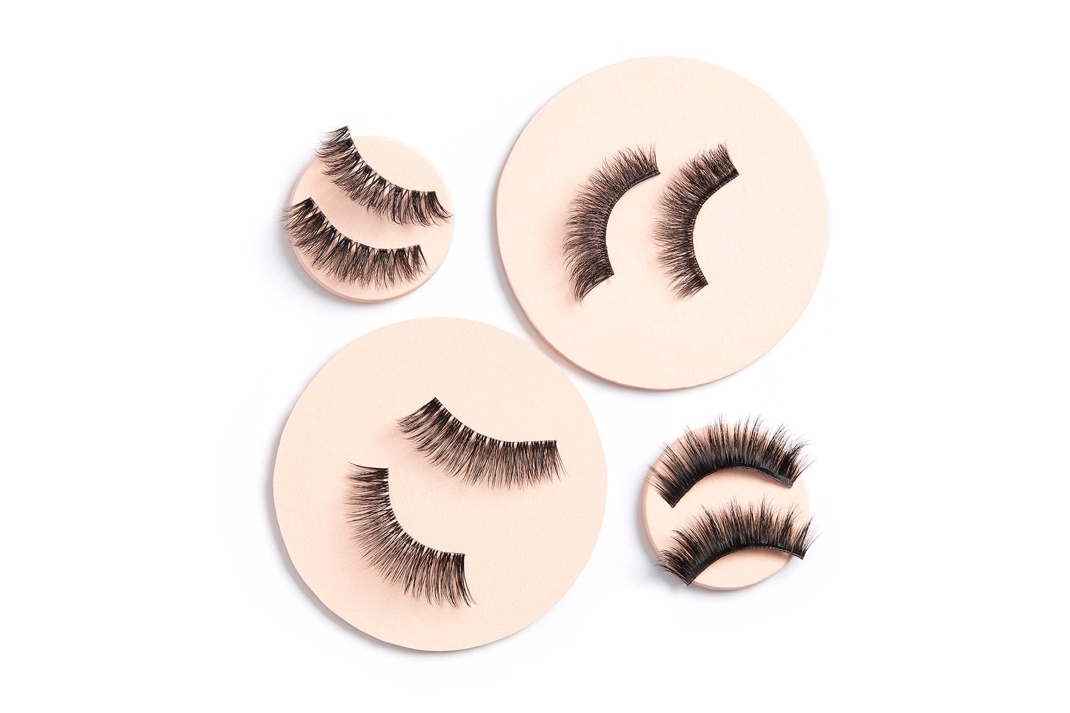 Flat lay of Ardell Magnetic Lashes pairs displayed on nude-toned round pads for visual texture
