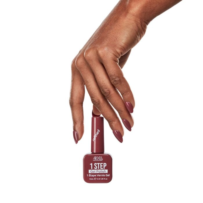 Model hand with Ardell Refined mauve manicure reaching for matching gel polish bottle against white background.
