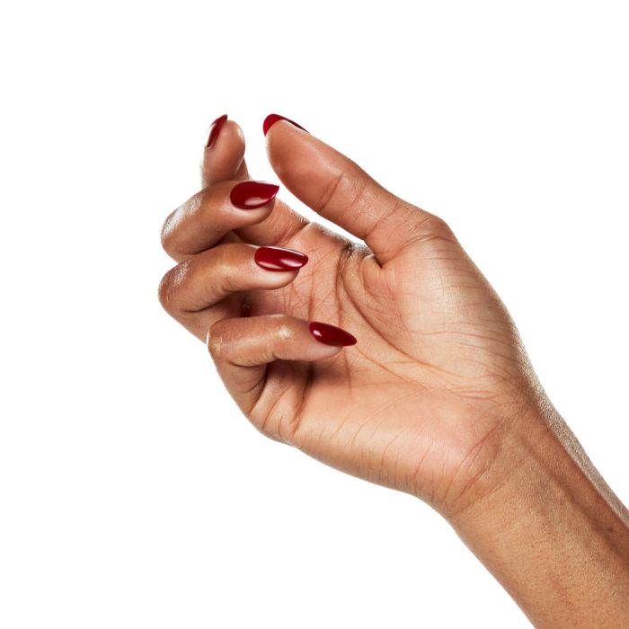 Natural hand pose with Ardell Feeling Frisky polish, highlighting its true red tone for a confident nail look.