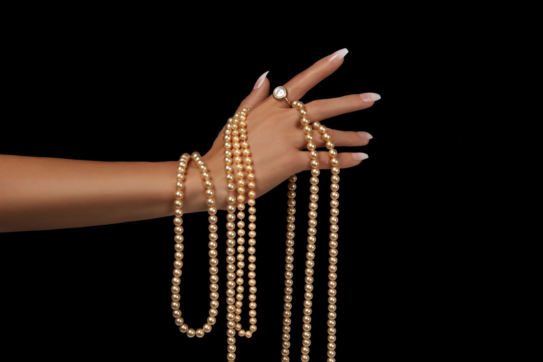 Almond-shaped French nails with pearl accents wrapped around hand, elegant and modern look.