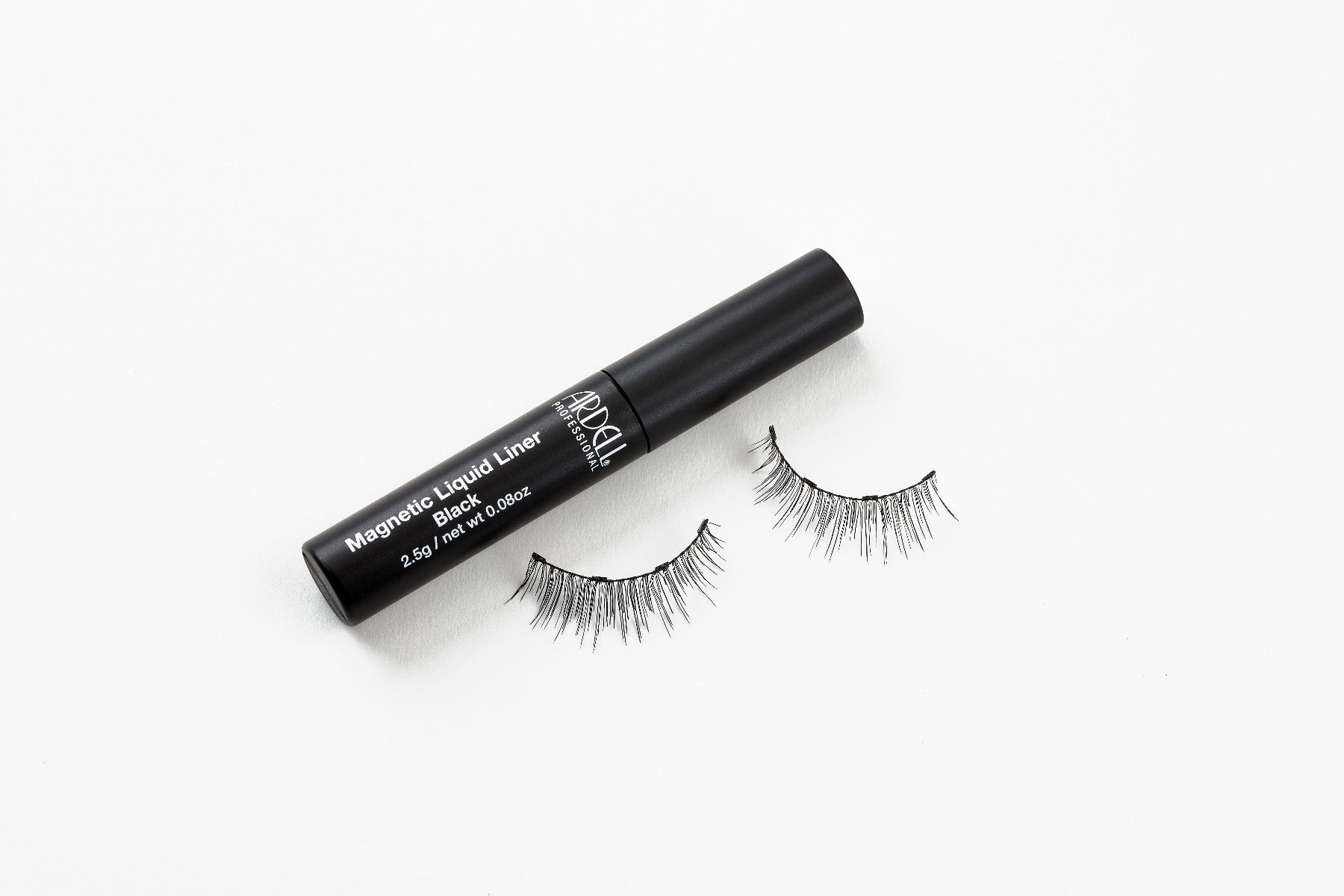 Capped Ardell Magnetic Liquid Liner bottle laying on its side with Lash 110 Wispies false lashes below