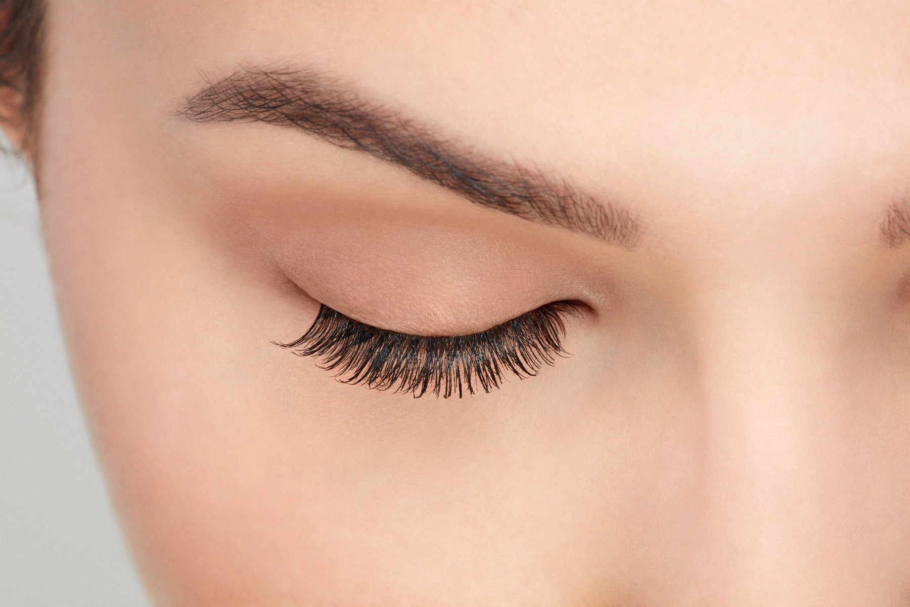 A model with a close right eye wearing Ardell Natural 110 showing how it looks undetectable & totally natural look