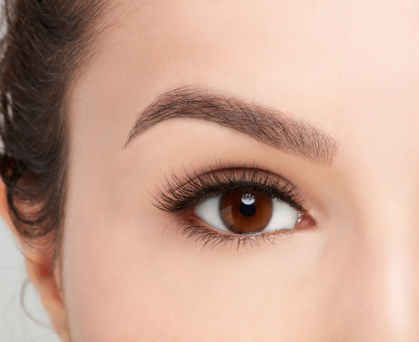Model on an open right eye wearing Ardell Pre-Cut Lashes 901 showing how it looks flared and natural on the eye