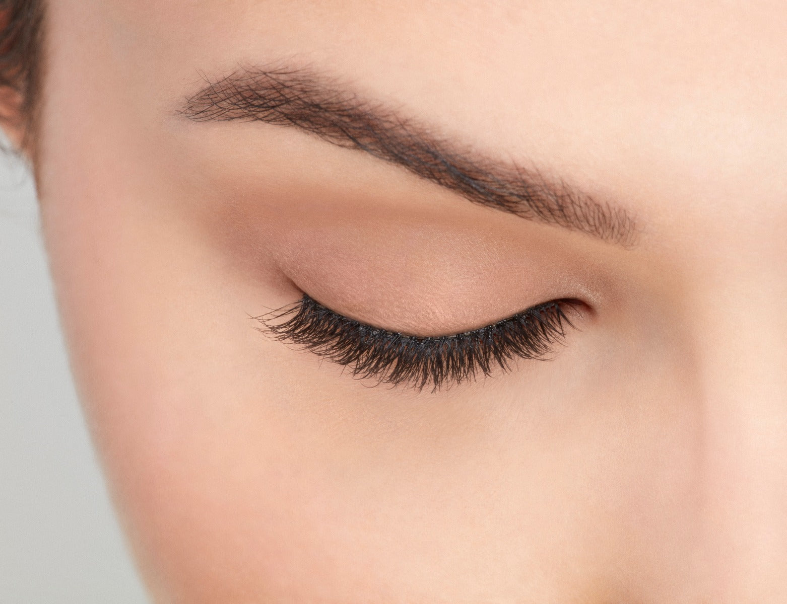 Model with closed right eye wearing Ardell Pre-Cut Lashes 901 showing how it looks flared and natural on the eye
