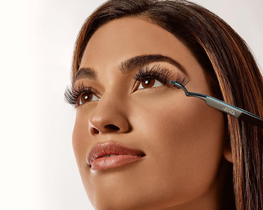 Model applying Ardell false lashes with precision applicator tool for a seamless lash look.