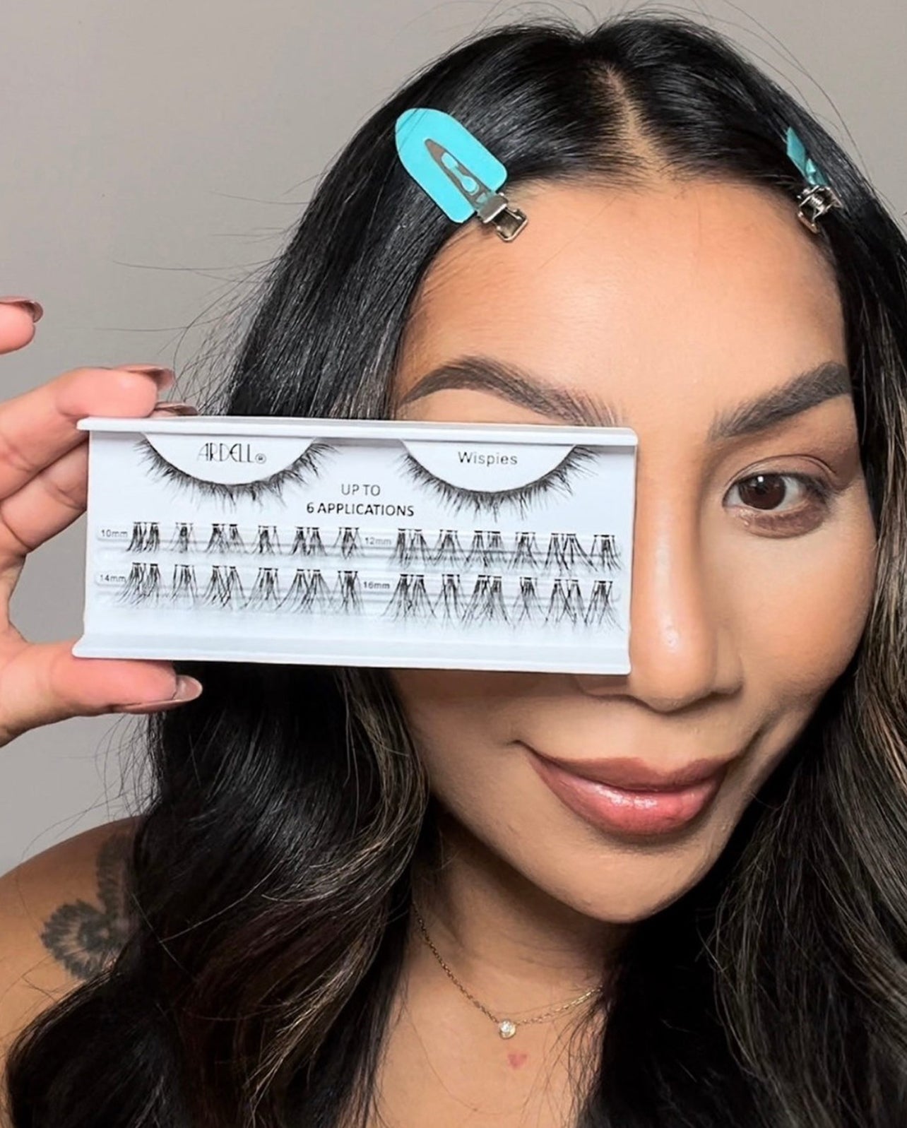 Model holding Ardell Wispies individual lash tray, showcasing assorted lengths for up to 6 applications.