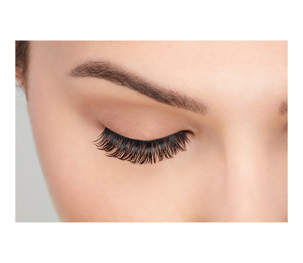 Front view of a model with one eye close wearing Ardell's Fauxmink Wispies to show how they look on the eye