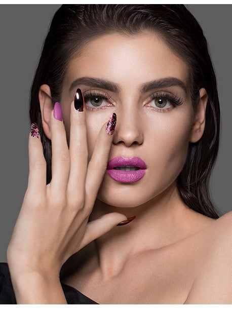 A fierce woman with her left hand on the right side of her face showing Ardell Nail Addict Artificial Nail-Chrome Pink Foil 