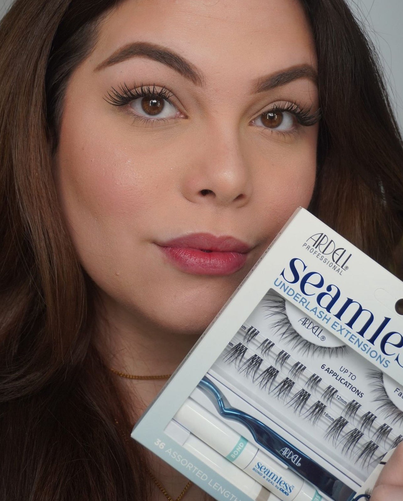 Model holding Ardell Seamless Underlash Extensions kit with tools and lashes for natural enhancement.