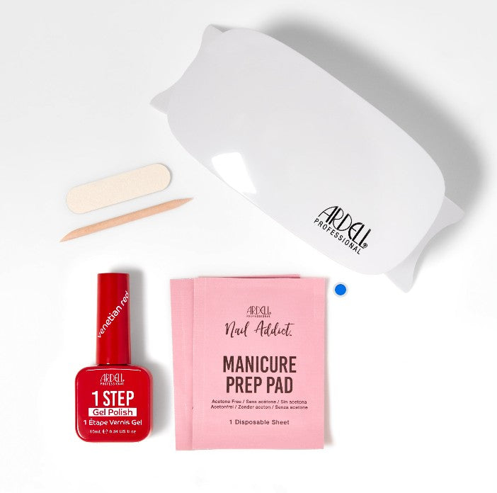 Flat lay of Ardell 1-Step Gel Starter Kit with LED lamp, Venetian Red polish, manicure prep pad, nail file, and orange stick.
