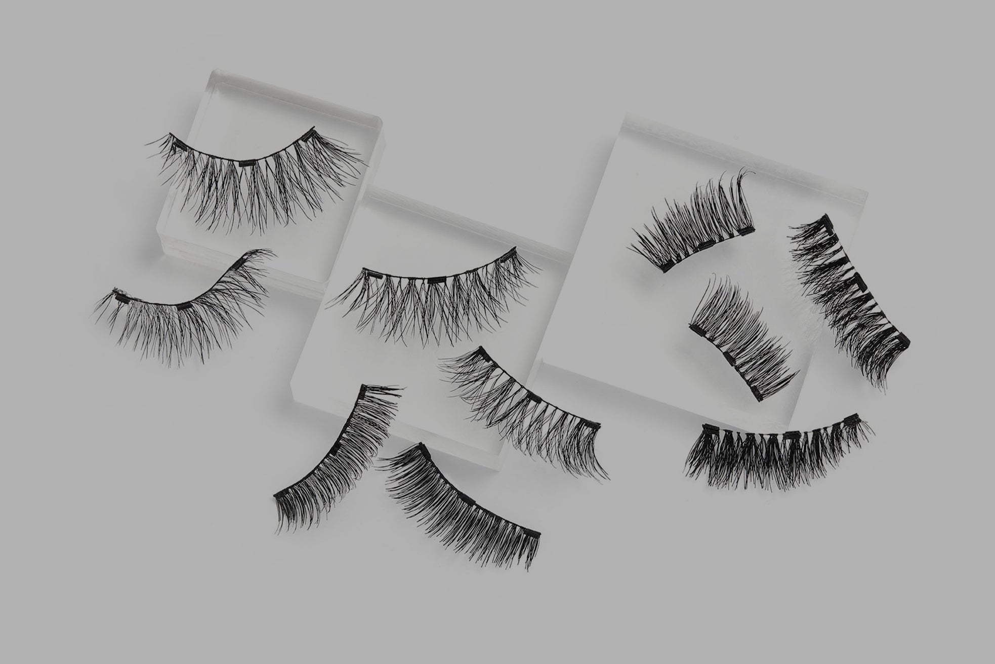 Set of false eyelashes on white paper against a gray background