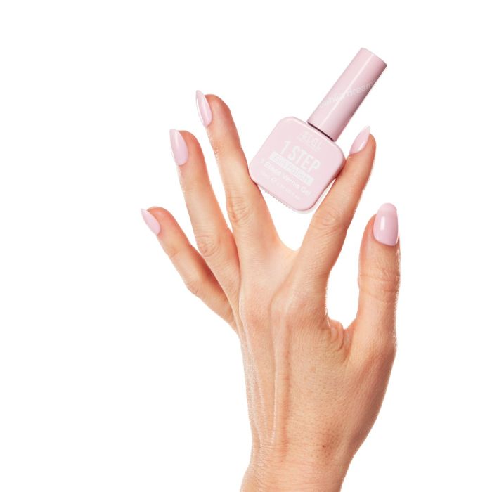 Model hand holding Ardell Dahlia Dreams gel polish bottle, showcasing glossy pastel pink manicure with an elegant flair.