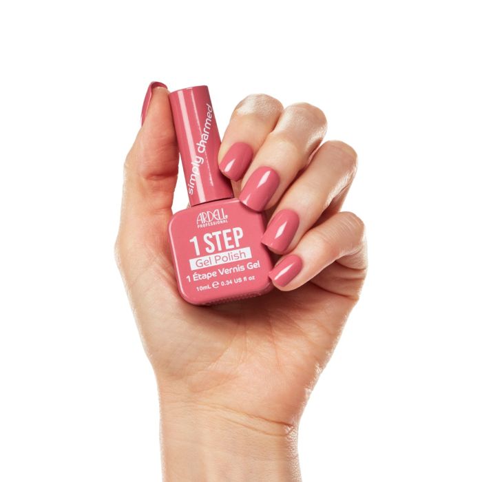 Model holding Ardell Simply Charmed gel polish with matching rosy pink manicure against white backdrop.