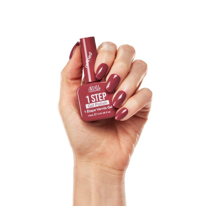 Hand holding Ardell Refined gel polish with deep mauve nails, showing glossy, elegant manicure finish.