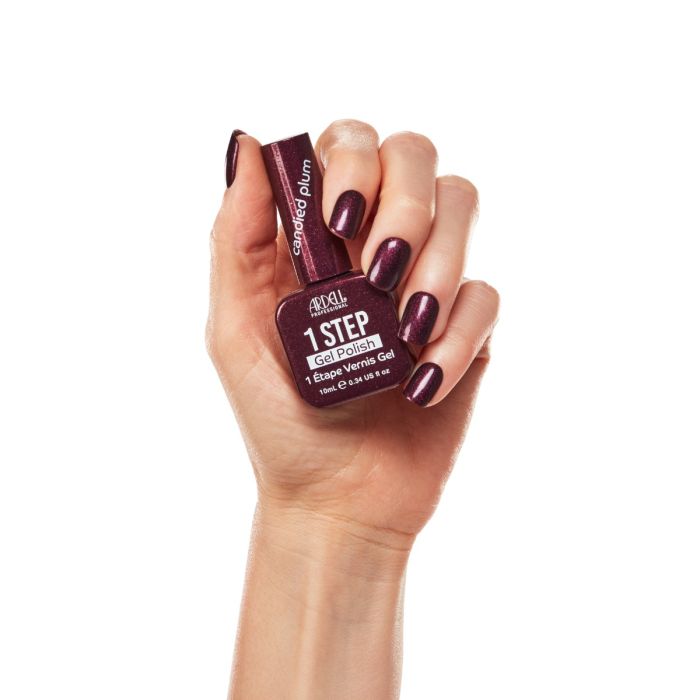 Hand model wearing Ardell Candied Plum polish, featuring a deep, shimmering berry-toned manicure.