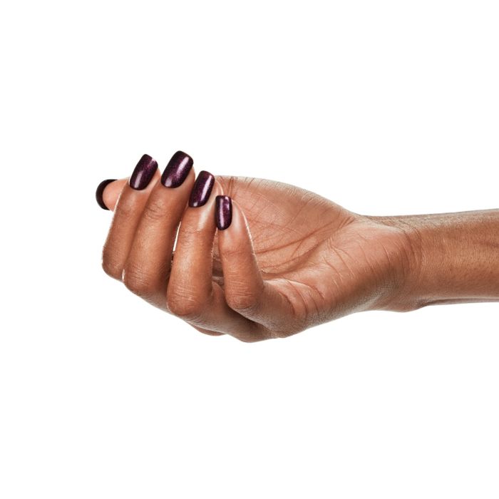 Natural hand pose with Ardell Candied Plum polish, offering a festive and dramatic deep plum manicure.