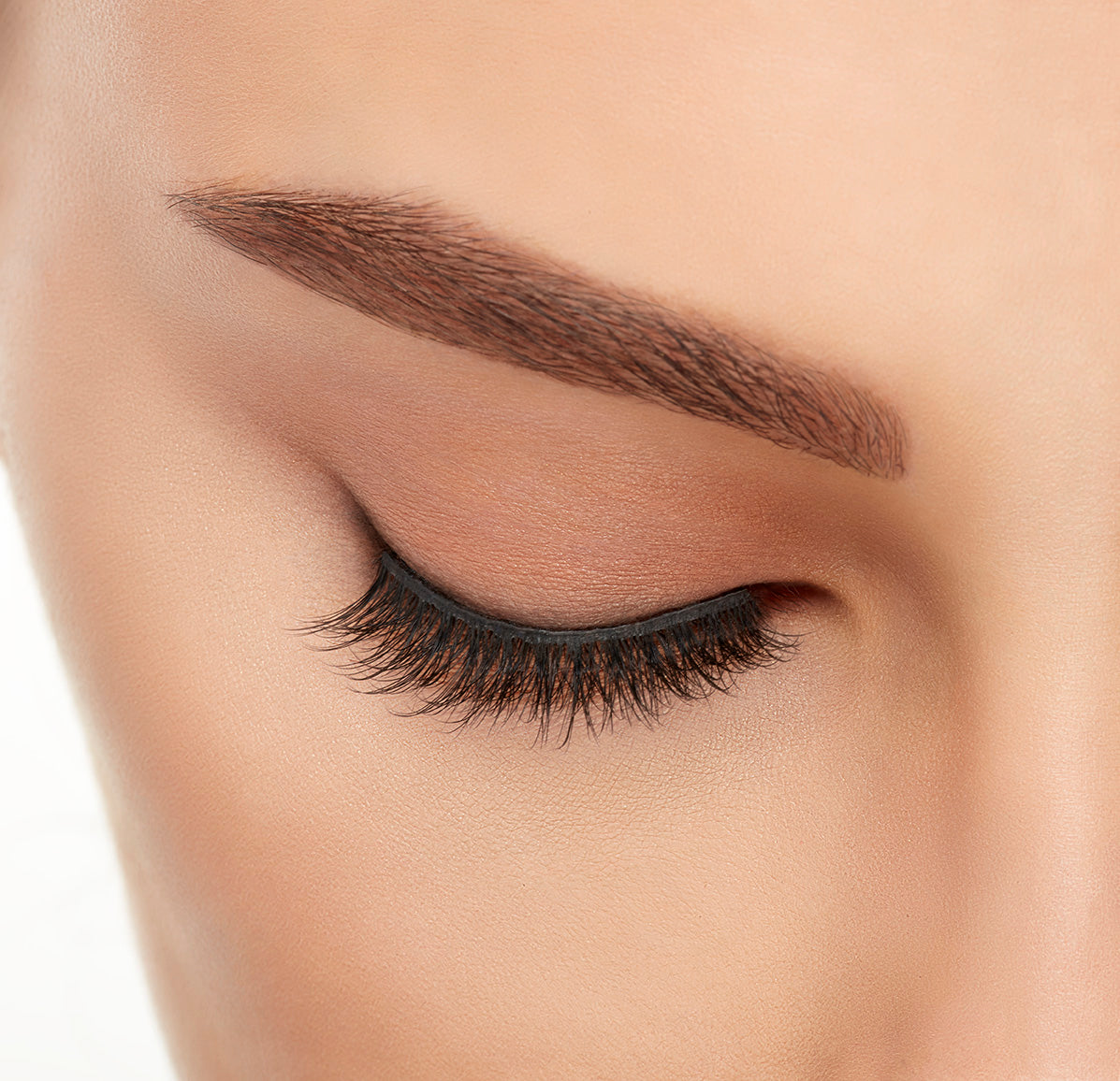 Close-up of a model's closed right eye wearing an Ardell Lift Effect 742 faux lash showing its curled round profile