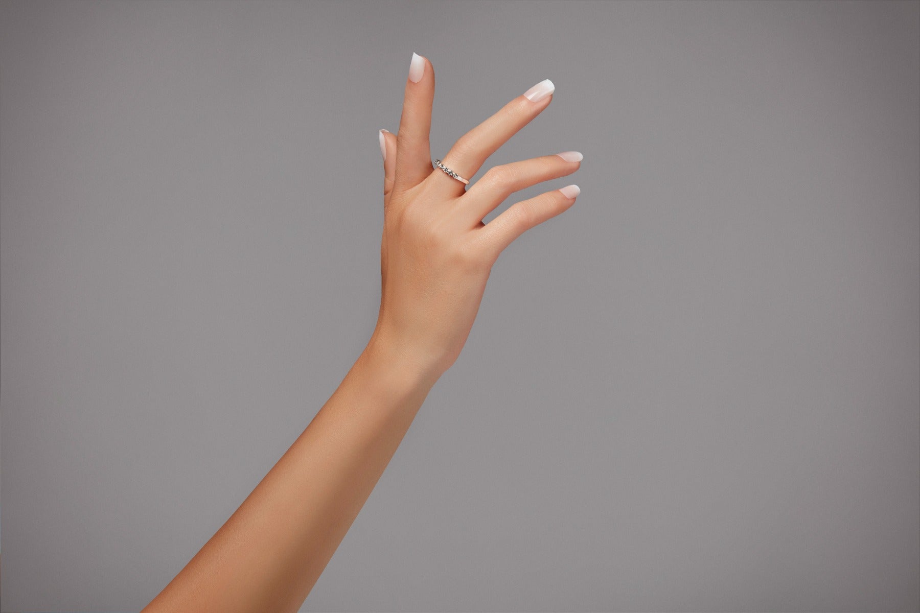 Light-toned hand model wearing Ardell short French ombré nails, perfect for everyday elegance.