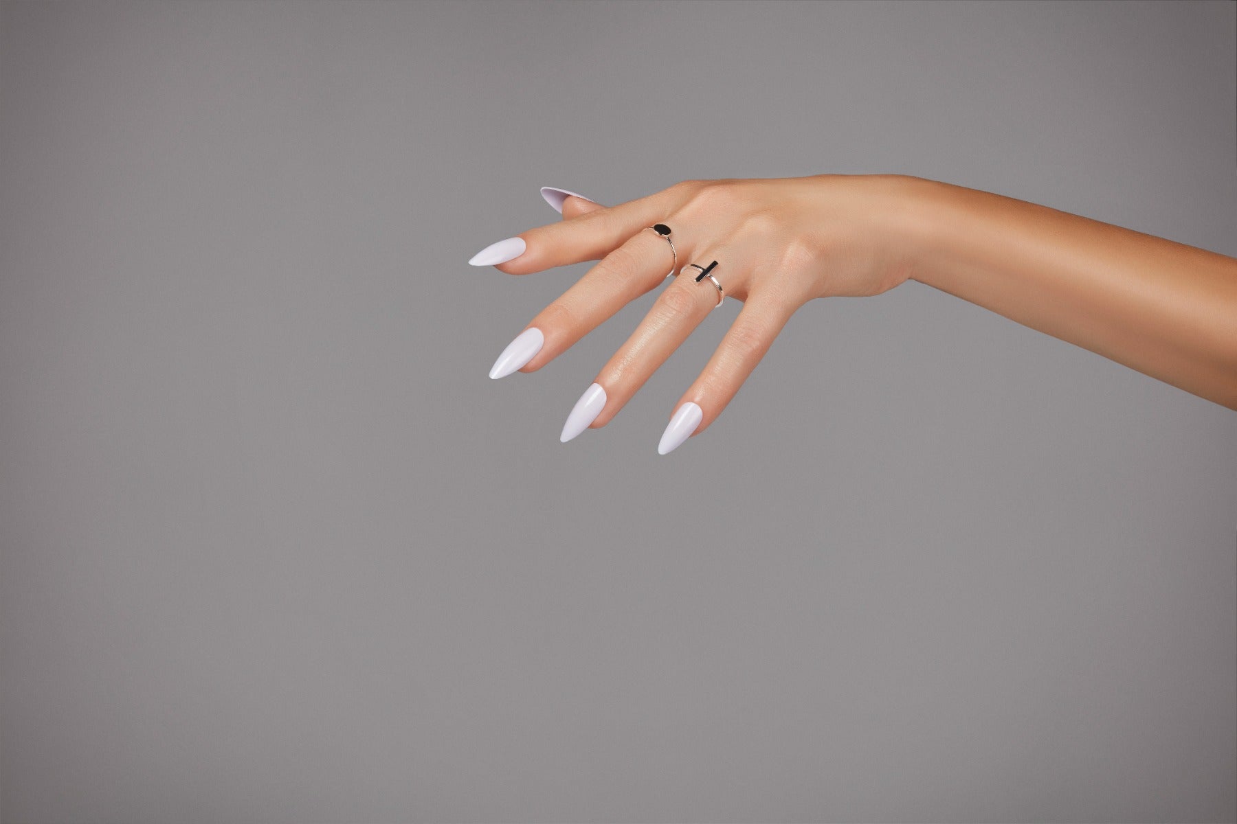 Glossy pale lilac press-on nails styled on fair skin with silver rings for a clean, elegant nail look.

