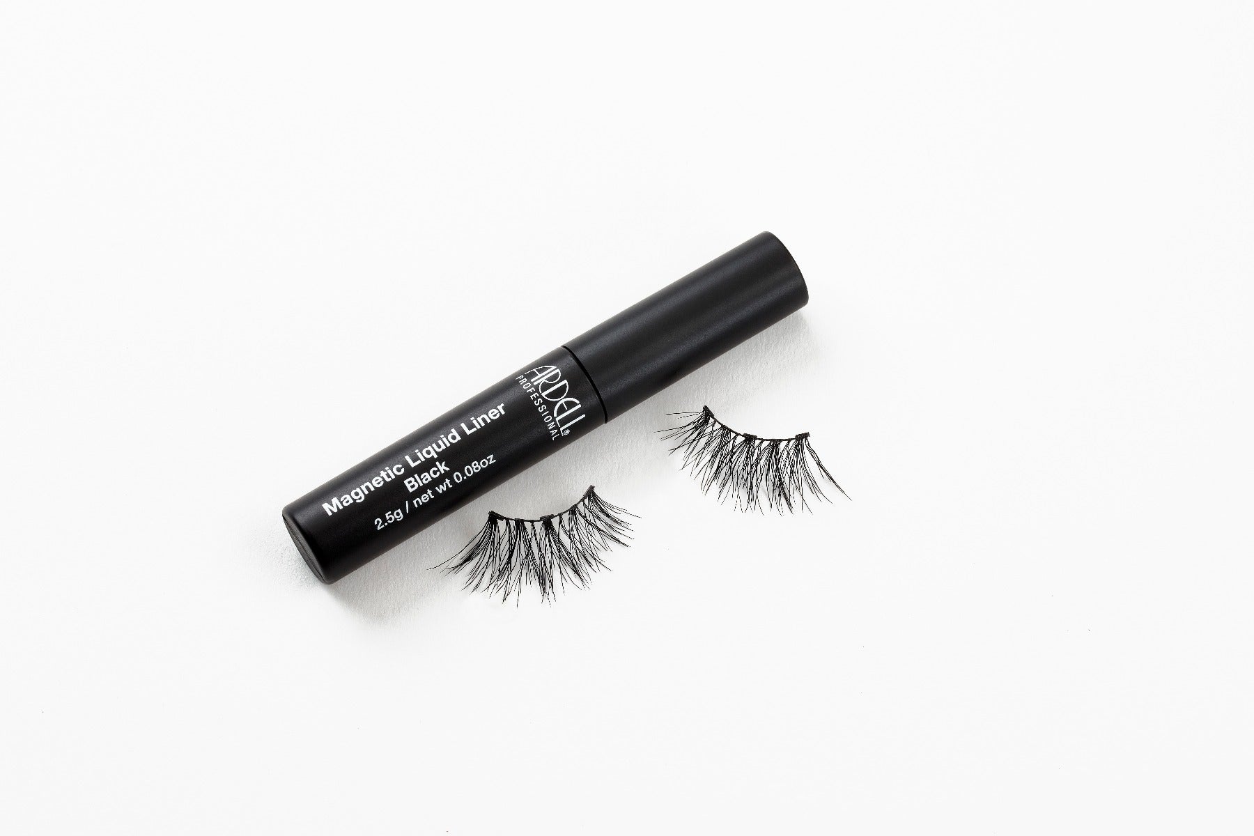 Capped Ardell Magnetic Liquid Liner bottle laying on its side with Accent 002 false lashes below