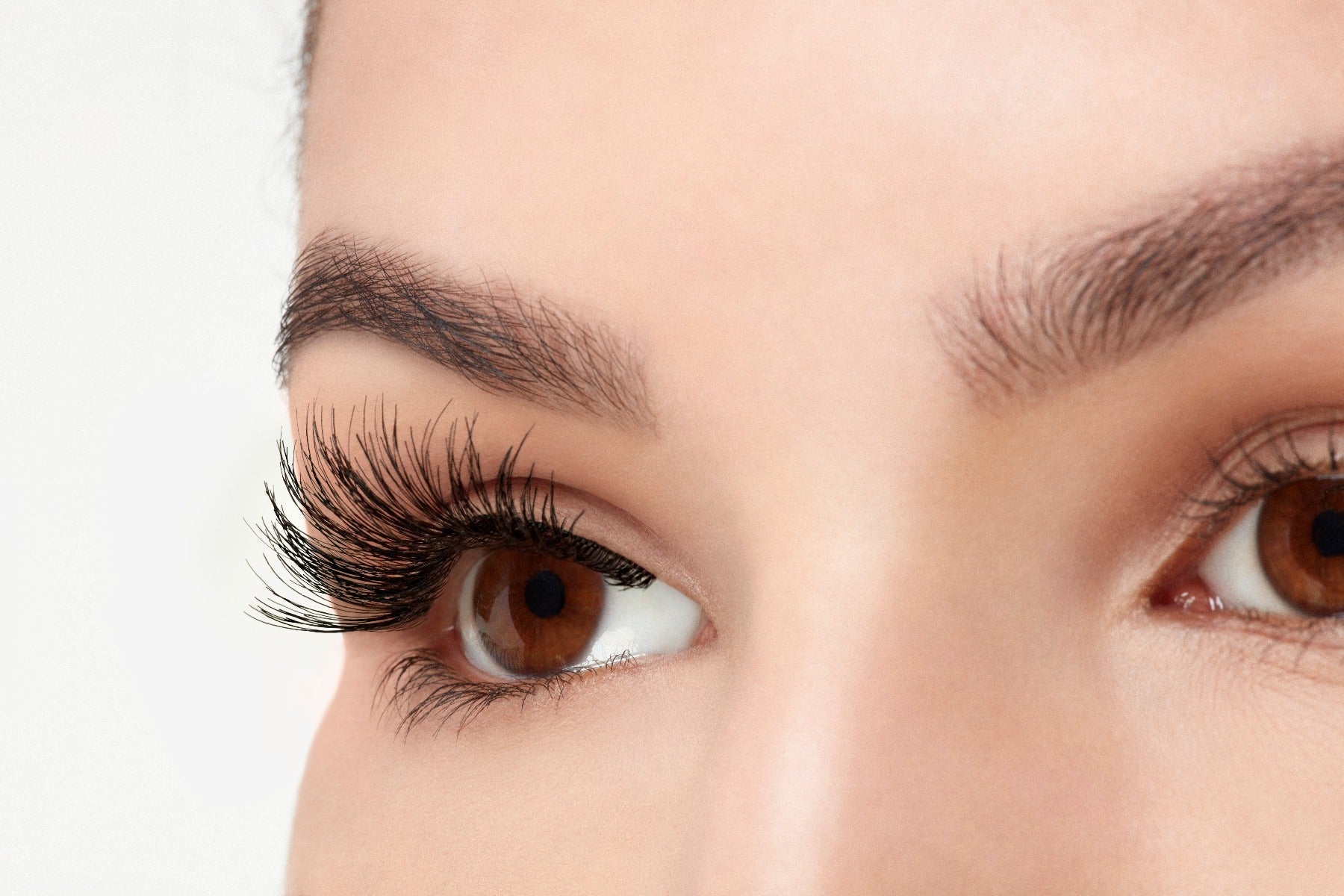 A model wearing Ardell Wispies 113 in side view showing its curly & extra-long length lash
