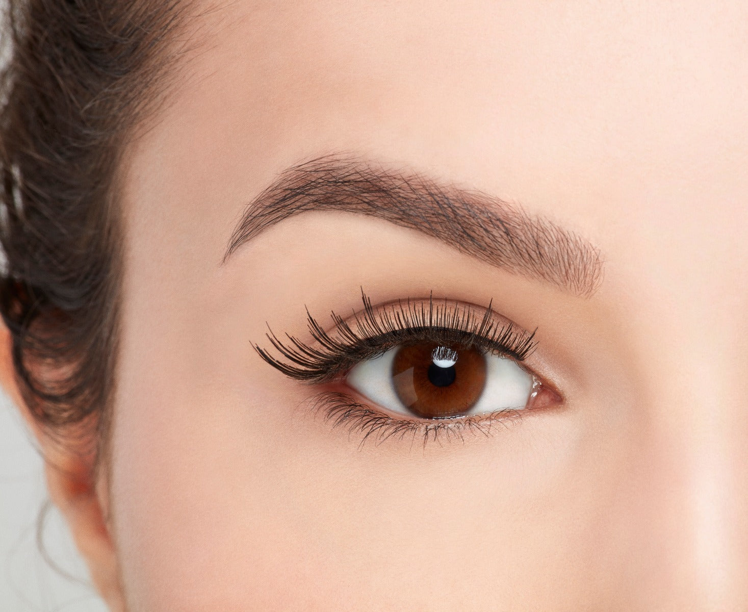 Close-up of a model's open right eye wearing a medium volume & length Ardell Natural 106 false lash