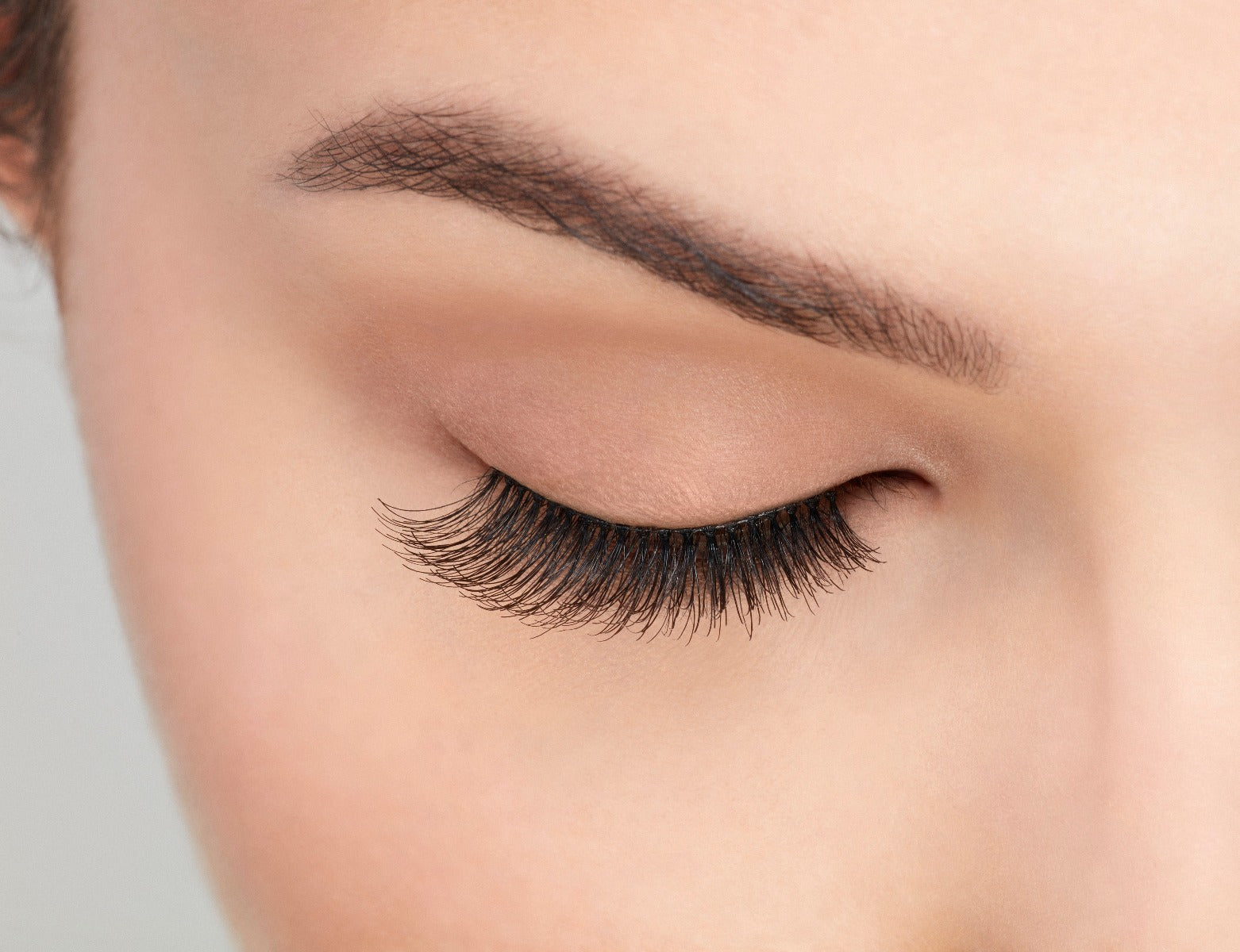 Close-up of a model's closed right eye wearing an Ardell Natural 117 false lash