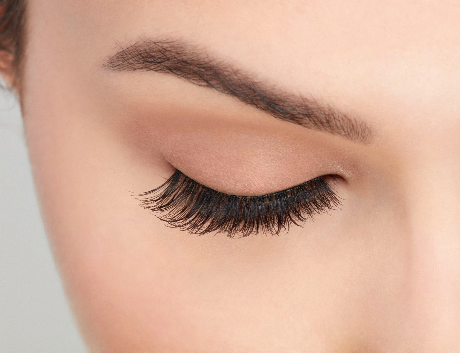 A model with closed eye wearing Ardell Studio Effects  Wispies with an accented full volume, curl & natural lash look