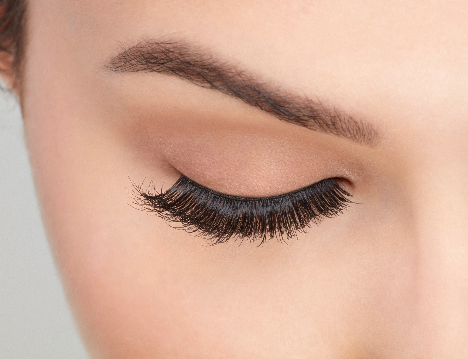 Close-up of a model's closed right eye wearing an Ardell Mega Volume 250 multi-layered faux lash