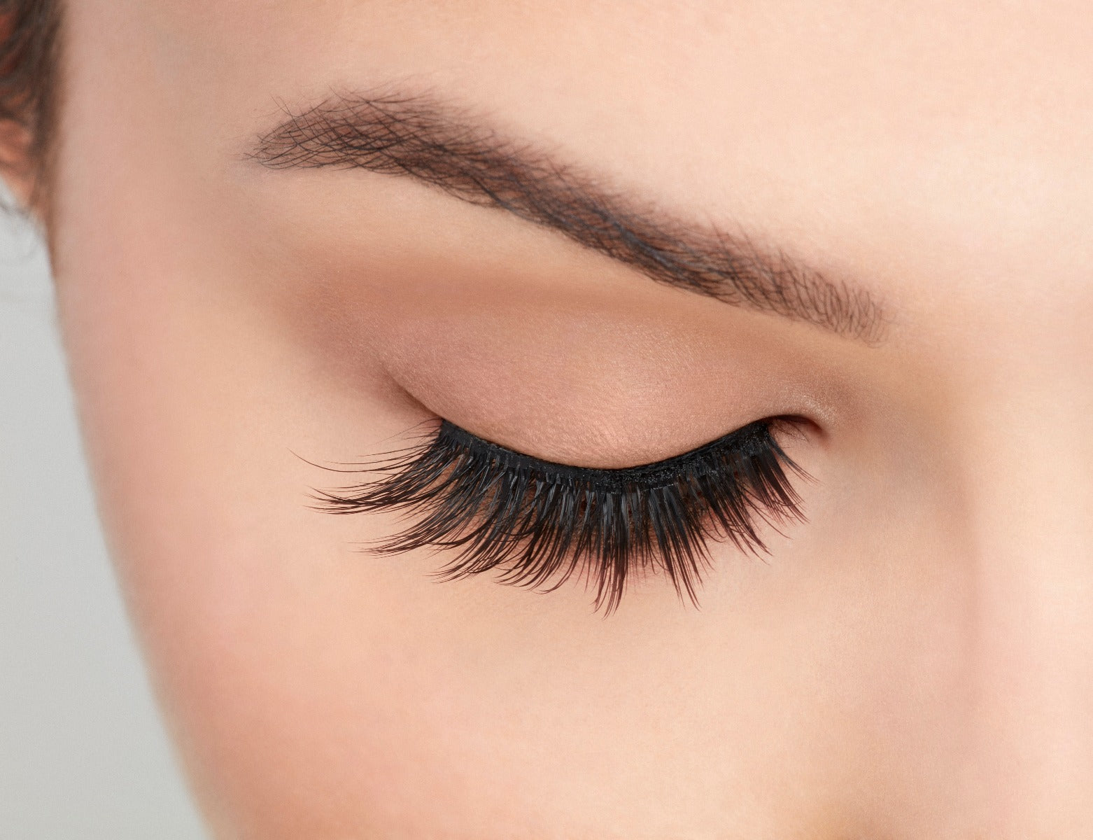 Close-up of a model's closed right eye wearing an Ardell Mega Volume 253 faux lash