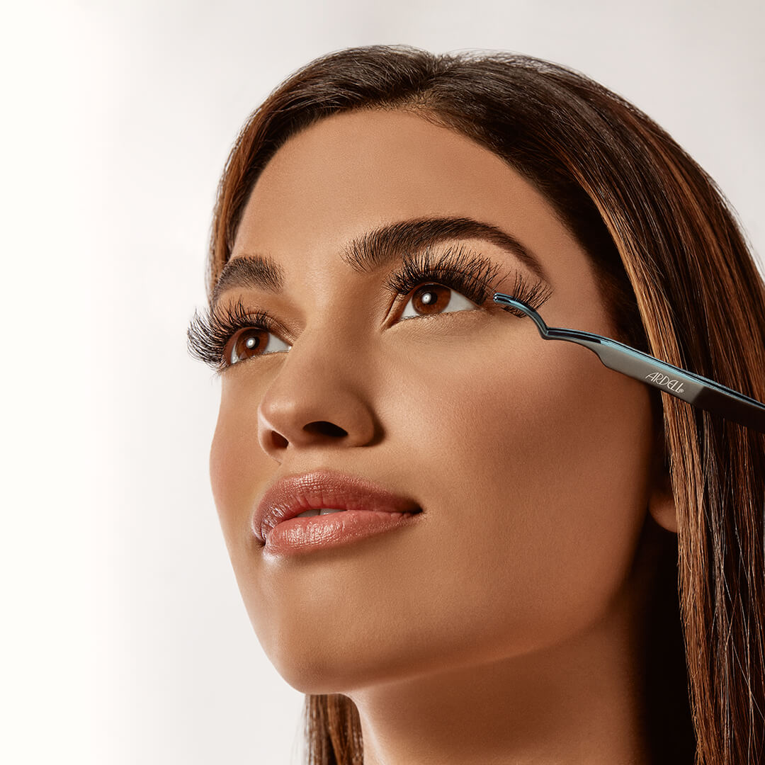 Model applying Ardell false lashes with precision applicator tool for a seamless lash look.