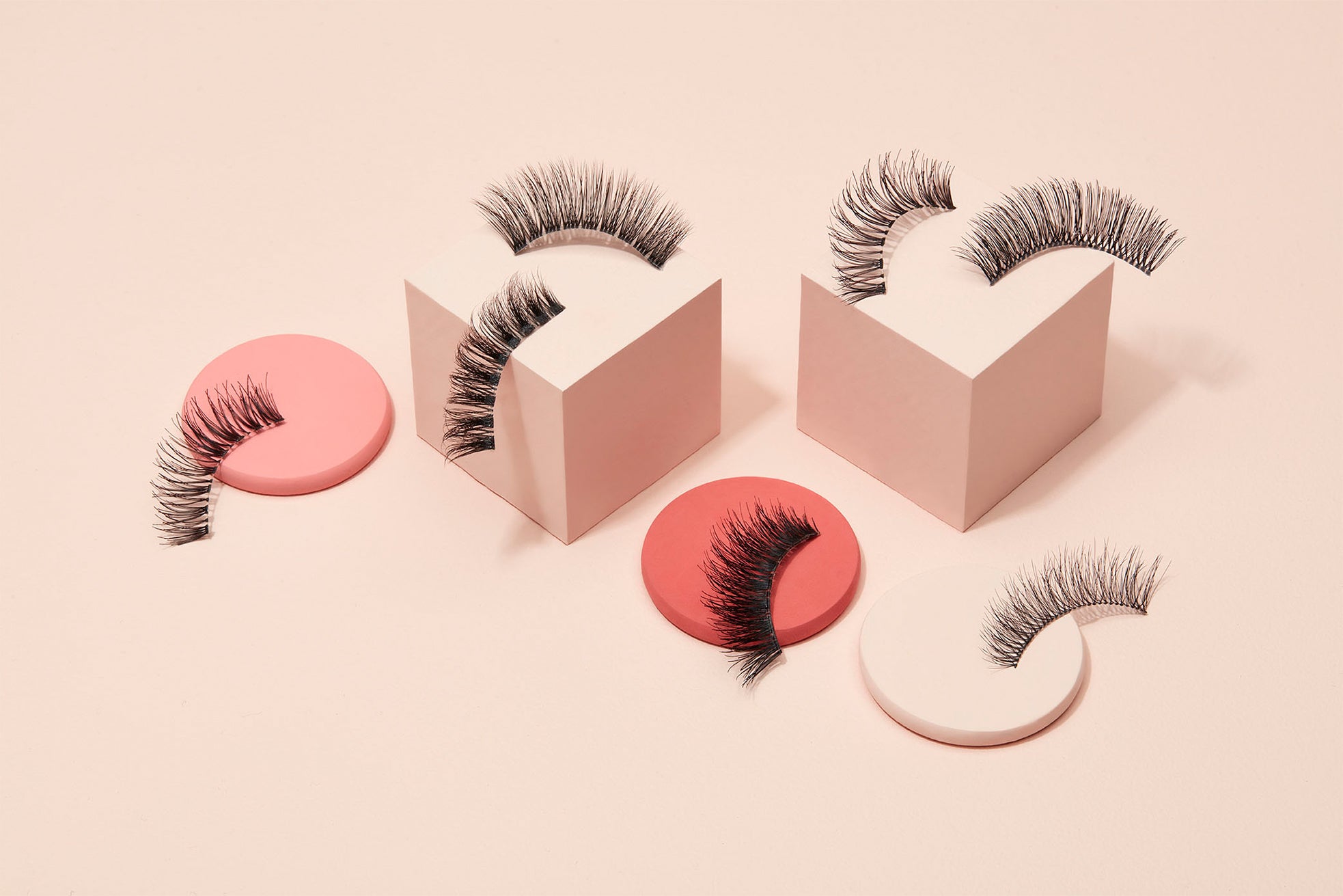 Lashes sitting on beige colored blocks as well as on pink and beige 3d circles.
